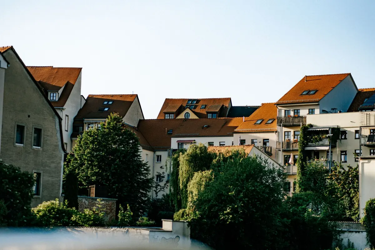 Mehrfamilienhäuser stehen an einer begrünten innerstädtischen Straße